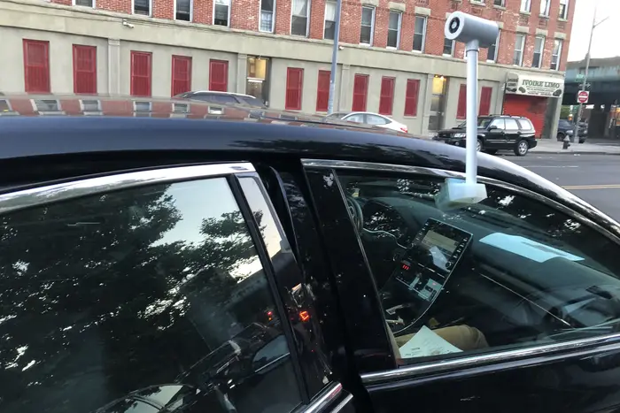 A white plastic sensor sticks out from a car's passenger window.